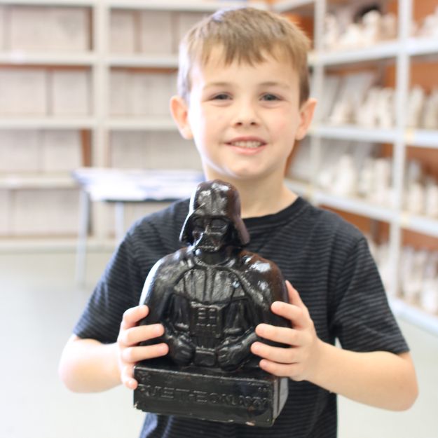 Child proudly displaying their ceramic masterpiece at Funtastik Labs, STEAM museum in Houston for ceramic painting and a hub for science and slime activities.